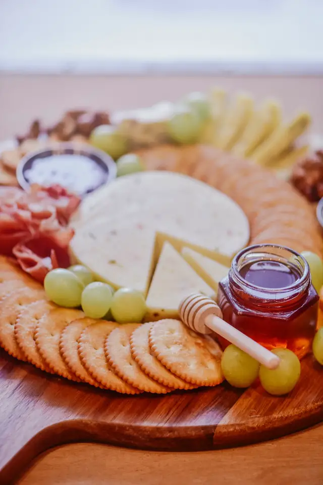 medlar jelly on a cheeseboard with meats, fruit, and cheeses